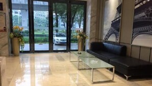 A lobby with a glass coffee table, a black sofa, and a large window with a view of a building and trees. - City Comfort Inn Shenzhen International Exhibition Center Tangwei Metro Station (Shenzhen)