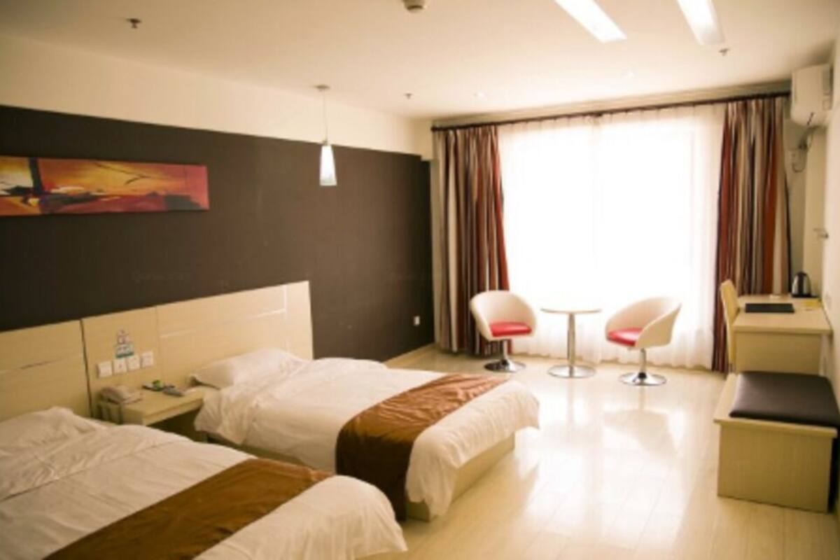 Habitación de hotel con dos camas, un escritorio, una silla, una mesita y un cuadro en la pared.