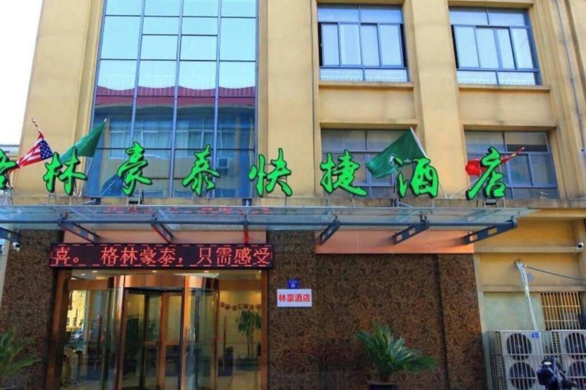 A hotel with a sign in Chinese characters, an American flag, and a sign indicating it is a hotel.