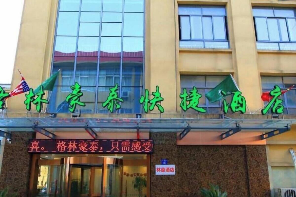A hotel with a sign in Chinese characters, an American flag, and a sign indicating it is a hotel.