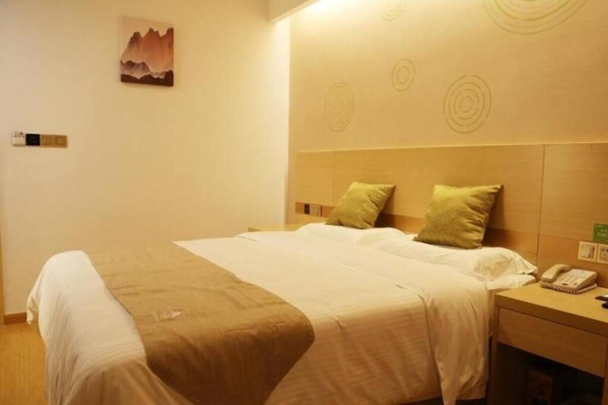 A hotel room with a bed, a nightstand, a telephone, and a painting on the wall.