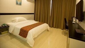 A hotel room with a bed, a desk, a chair, a TV, and a window with curtains. - Greentree Alliance Yancheng Sheyang County Xixin Temple Hotel (Yancheng)
