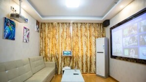 A room with a sofa, a table, a projector screen, and a refrigerator. - Greentree Alliance Yancheng Sheyang County Xixin Temple Hotel (Yancheng)