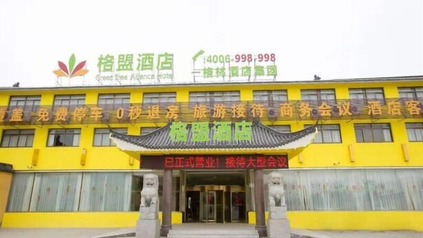 A hotel with a yellow facade, a traditional Chinese architectural entrance, and a sign indicating it is part of the Green Tree Alliance Hotel group. - Greentree Alliance Yancheng Sheyang County Xixin Temple Hotel (Yancheng)