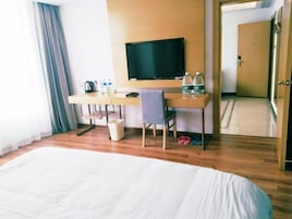 Una habitación de hotel con una cama grande, un escritorio con televisor y una silla.