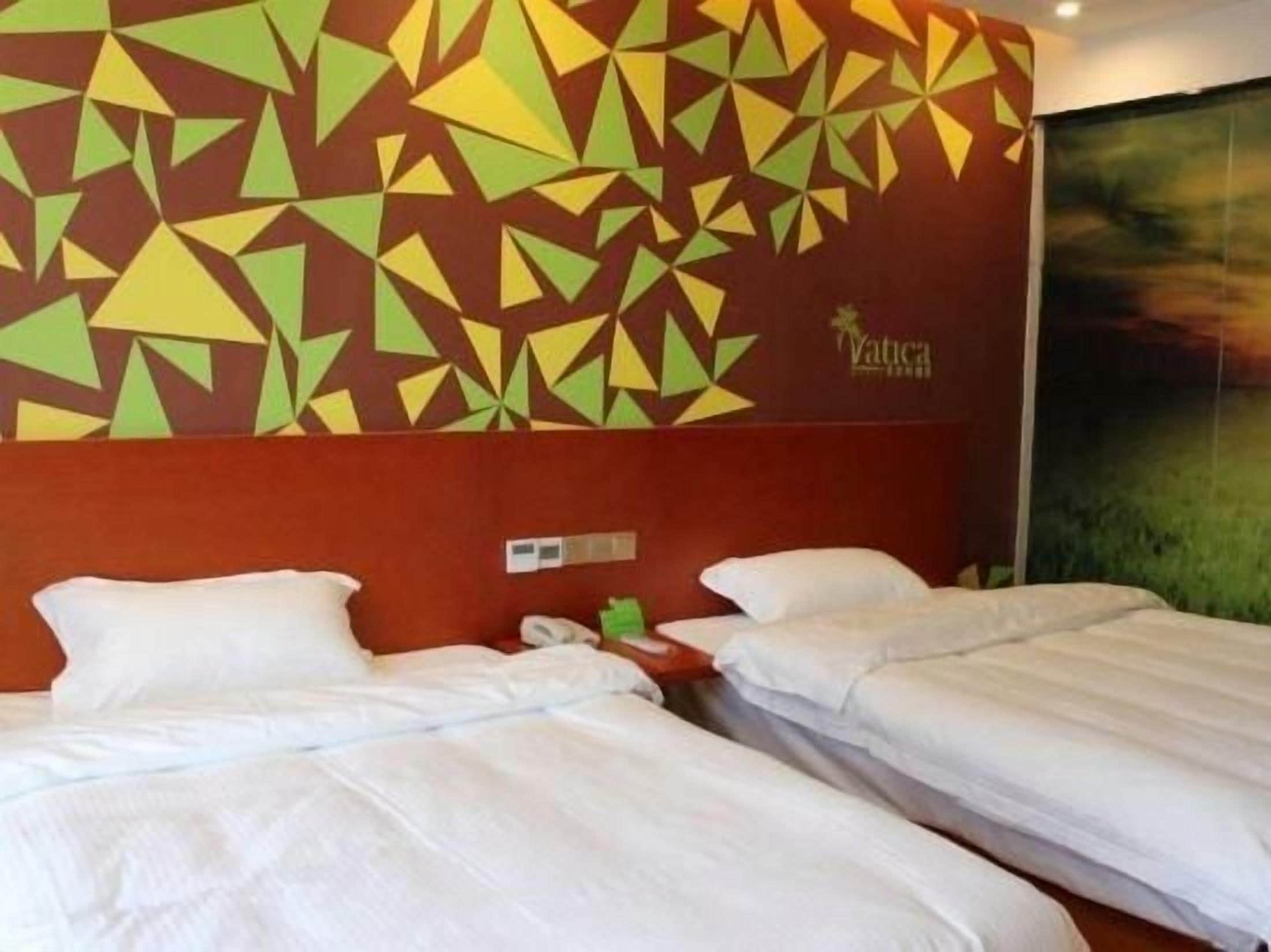A hotel room with two beds, a wall with geometric patterns, and a painting.