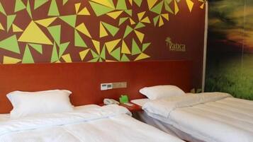 A hotel room with two beds, a red headboard, and a geometric wall design.