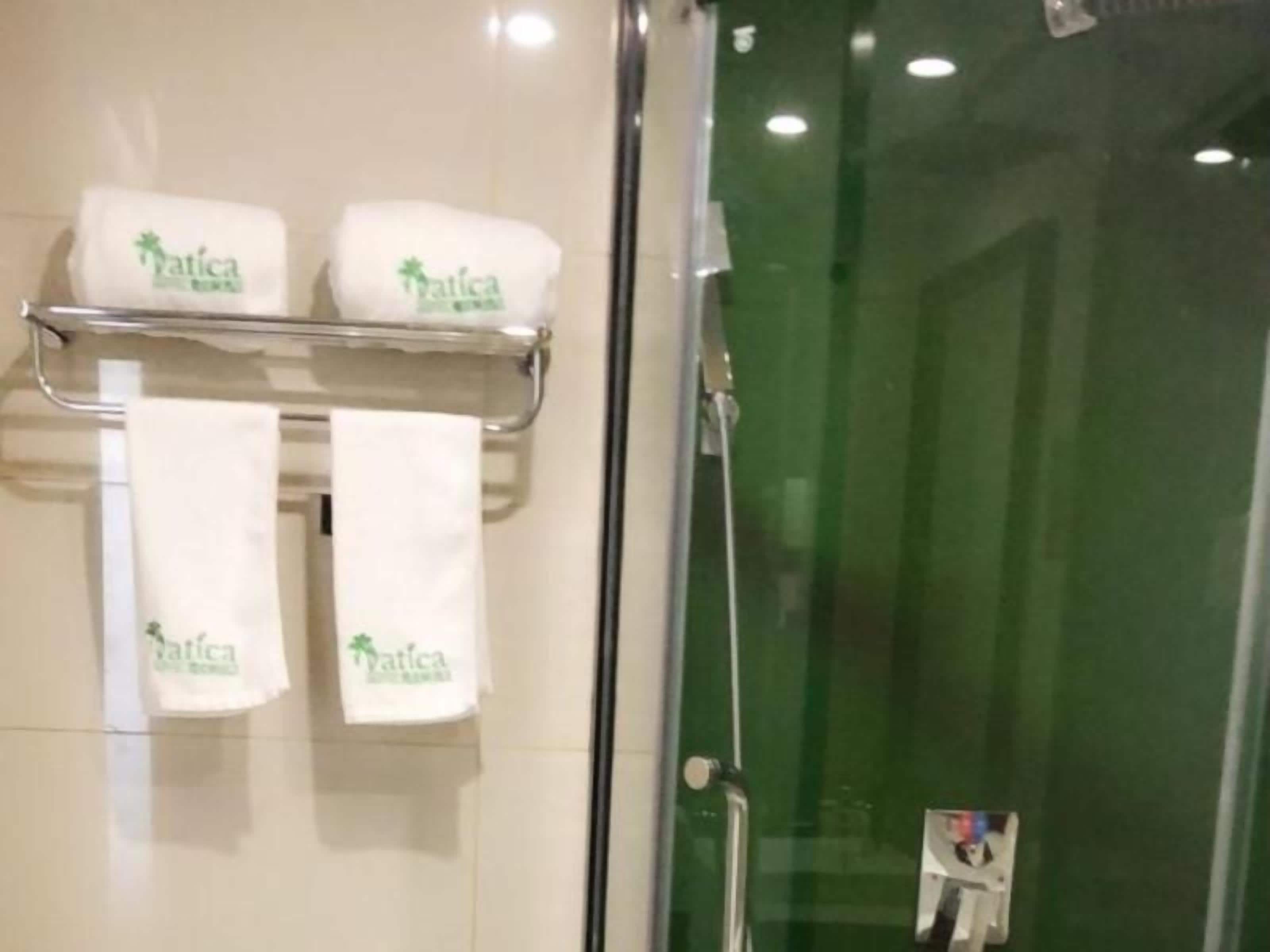 Une salle de bain dotée d’une porte de douche en verre, d’un porte-serviettes avec trois serviettes blanches et d’un espace de douche délimité par des parois en verre.