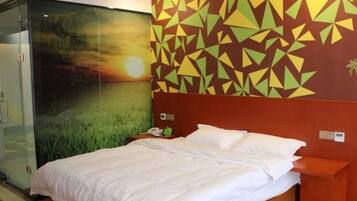 A hotel room with a bed, a nightstand, a glass partition, and a wall with geometric patterns.