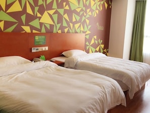 A hotel room with two beds, a wall clock, and a sign indicating amenities.