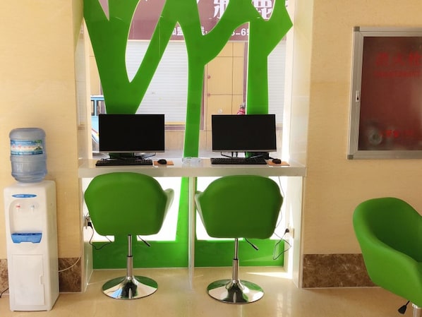 A reception area with two computer monitors, a water dispenser, and two green chairs.