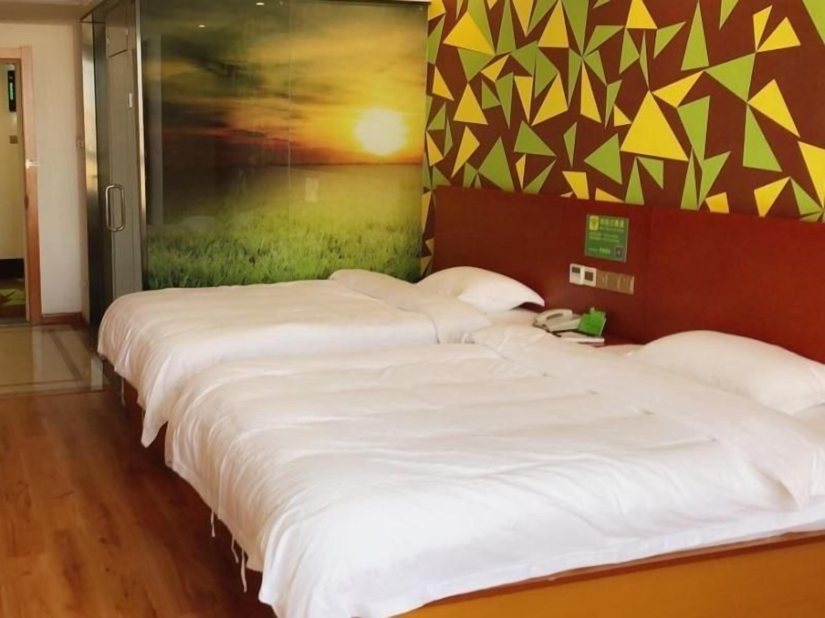 A hotel room with two beds, a large window, and a geometric-patterned wall.