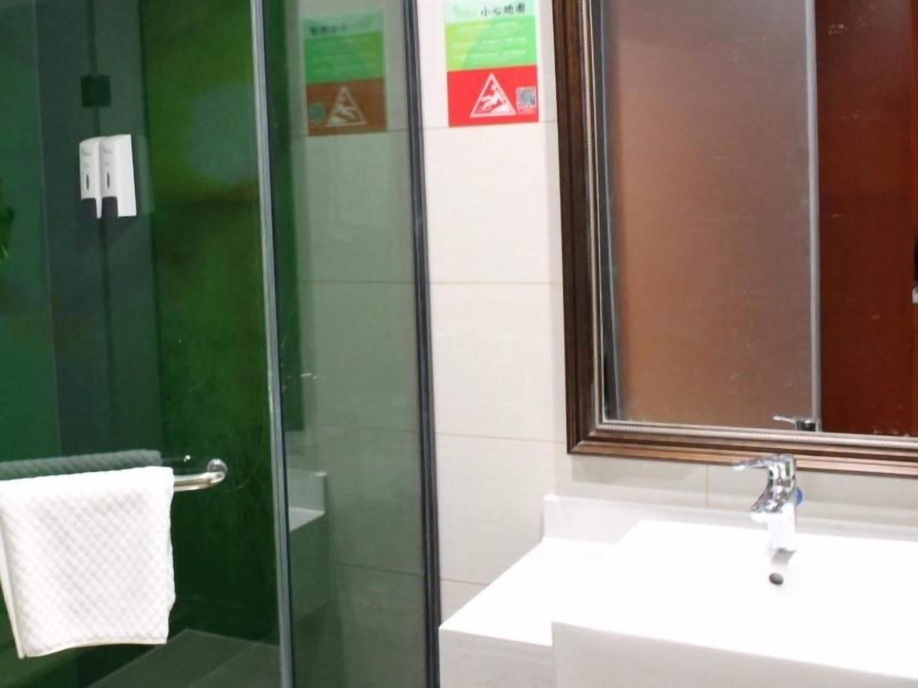 A bathroom with a glass shower enclosure, a white sink, and a mirror.