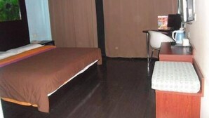 Ein Hotelzimmer mit einem Bett, einem Schreibtisch mit Stuhl, einem Fernseher und einer Kaffeemaschine.