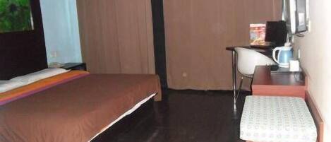 A hotel room with a bed, a desk with a chair, a television, and a coffee maker.