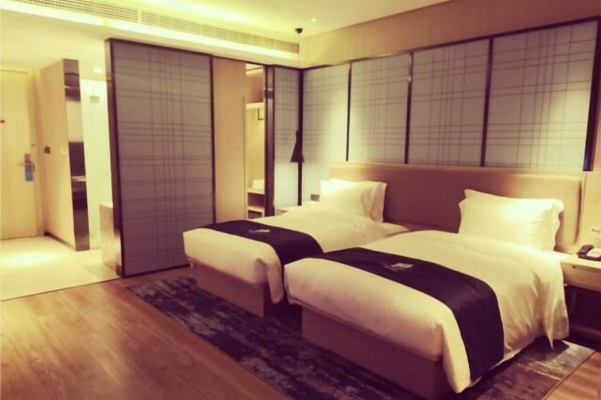 A hotel room with a double bed, a bedside table, a nightstand, a wardrobe, and a sliding door.