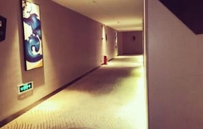A hallway with a patterned floor, a wall-mounted light, and a door at the end.