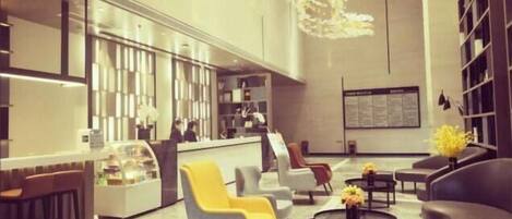 A modern lobby with a reception desk, seating area, and a large chandelier.