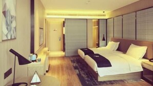 Una habitación de hotel moderna con una cama grande, mesitas de noche, un escritorio y un espejo.
