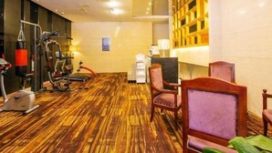 Una camera d'albergo con pavimento in legno, attrezzature per esercizi, una scrivania e un lampadario.