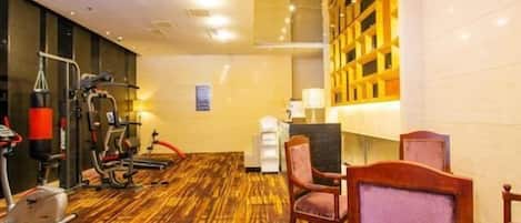 A hotel room with a wooden floor, exercise equipment, a desk, and a chandelier.
