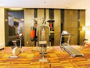 Gimnasio de hotel con equipo cardiovascular, una cinta de correr y un saco de boxeo.