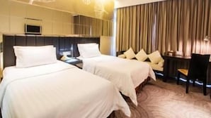 Una camera d'albergo con due letti, una scrivania e una sedia.