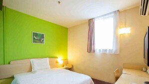 A hotel room with a bed, bedside table, lamp, and a window with curtains. - 7days Inn Chain Hotel (Beijing)