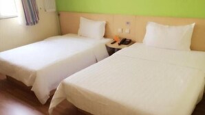 Two single beds with white linens, a bedside table with a phone and a lamp, and a green wall. - 7days Inn Chain Hotel (Beijing)