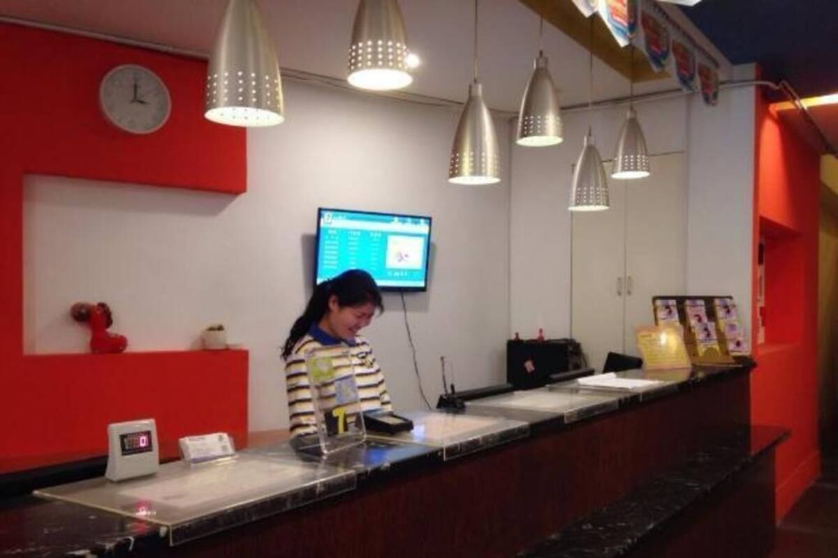 A reception desk with a digital screen, a clock, and hanging pendant lights.