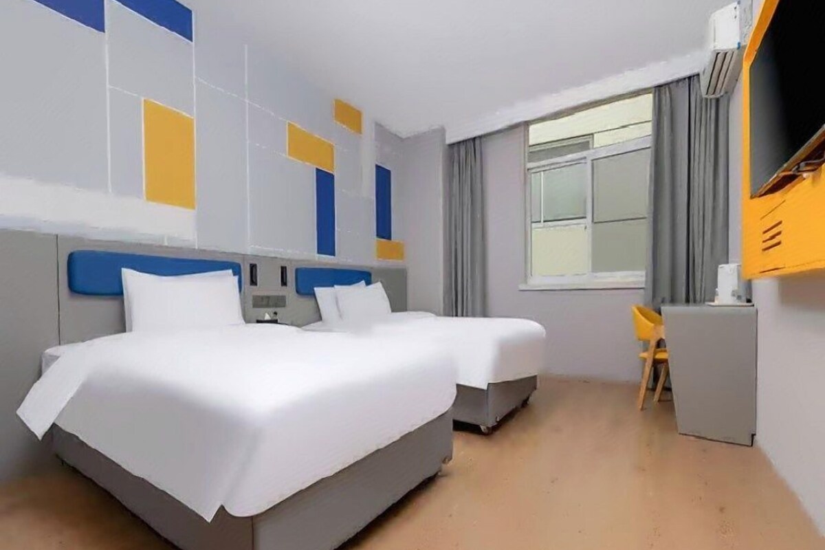 Une chambre d’hôtel avec deux lits, un bureau et une fenêtre.