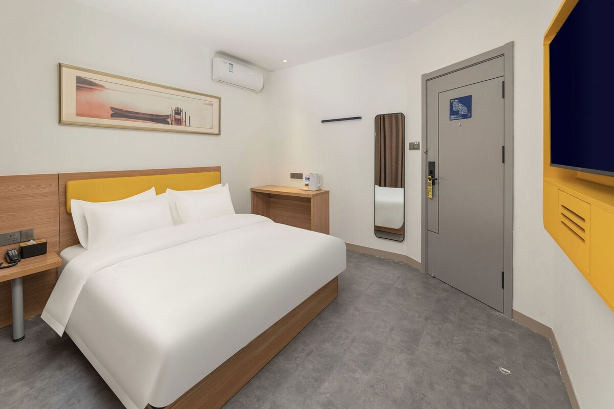 Une chambre d’hôtel avec un lit, une table de chevet, un miroir et une porte.