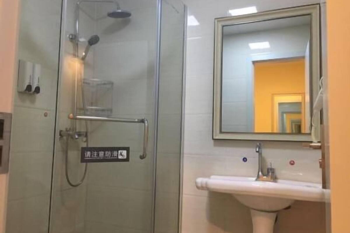 A bathroom with a glass shower enclosure, a sink, and a mirror.