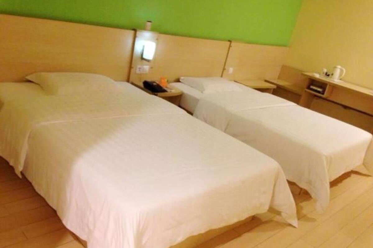 A hotel room with two beds, a green wall, and wooden flooring.