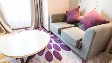 Ein Zimmer mit einer Couch, zwei Kissen, einem runden Tisch und einem gemusterten Teppich.
