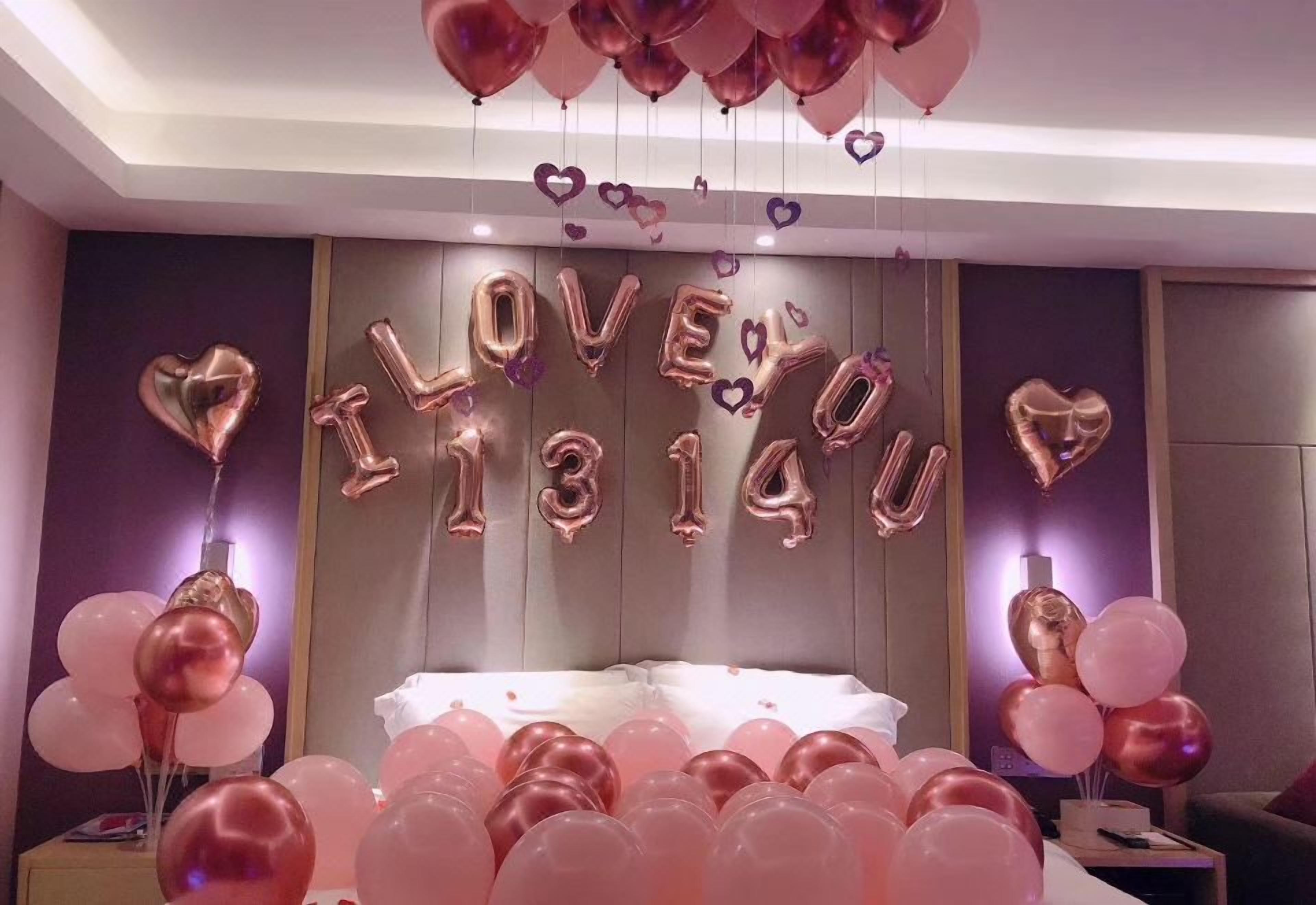 Una habitación con una cama, globos y una pared donde se lee 'I LOVE YOU' con globos.