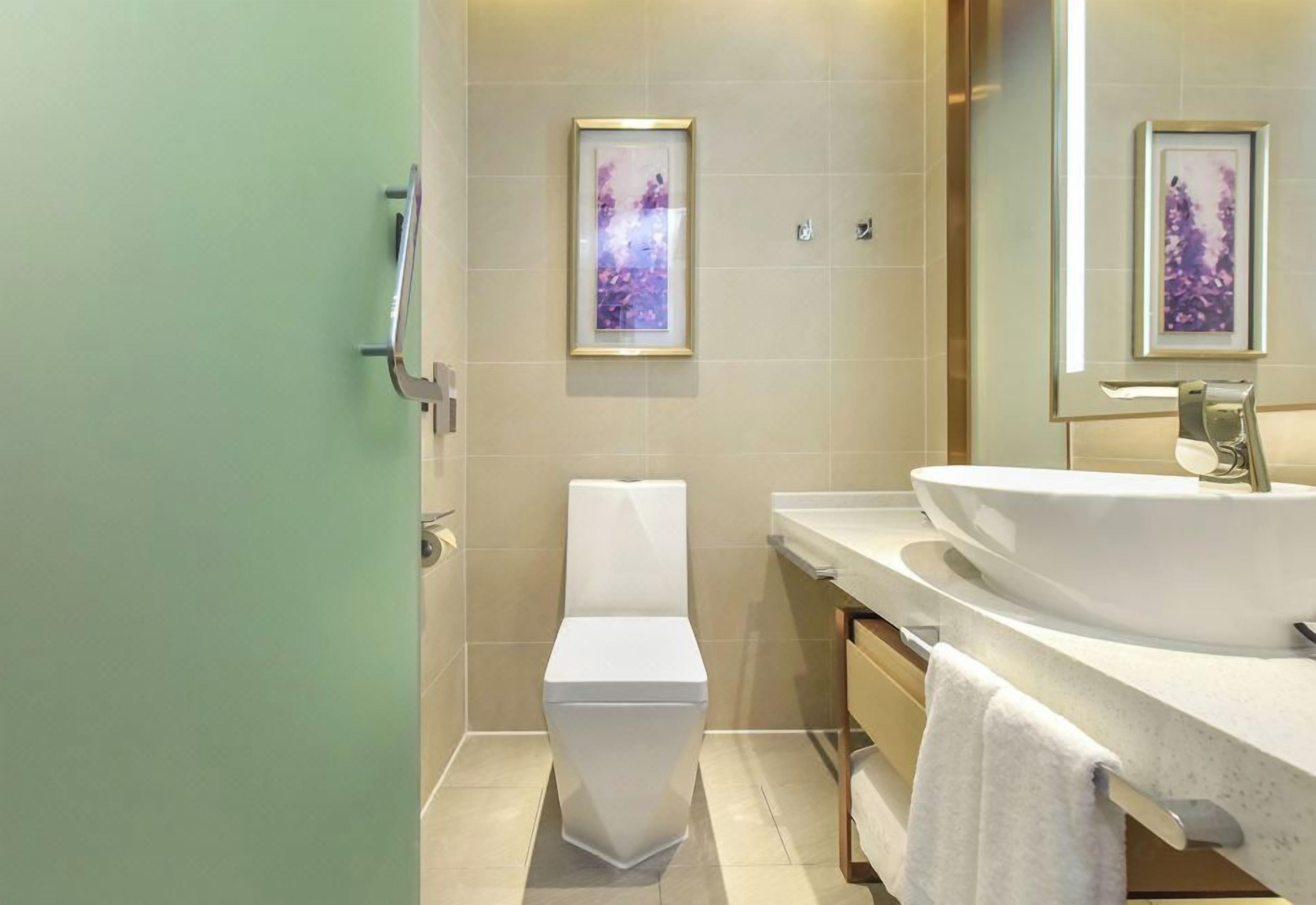 A modern bathroom with a toilet, sink, and framed artwork on the wall.