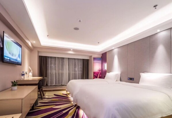 A modern hotel room with a large bed, a desk, a television, and a view of the outdoors.