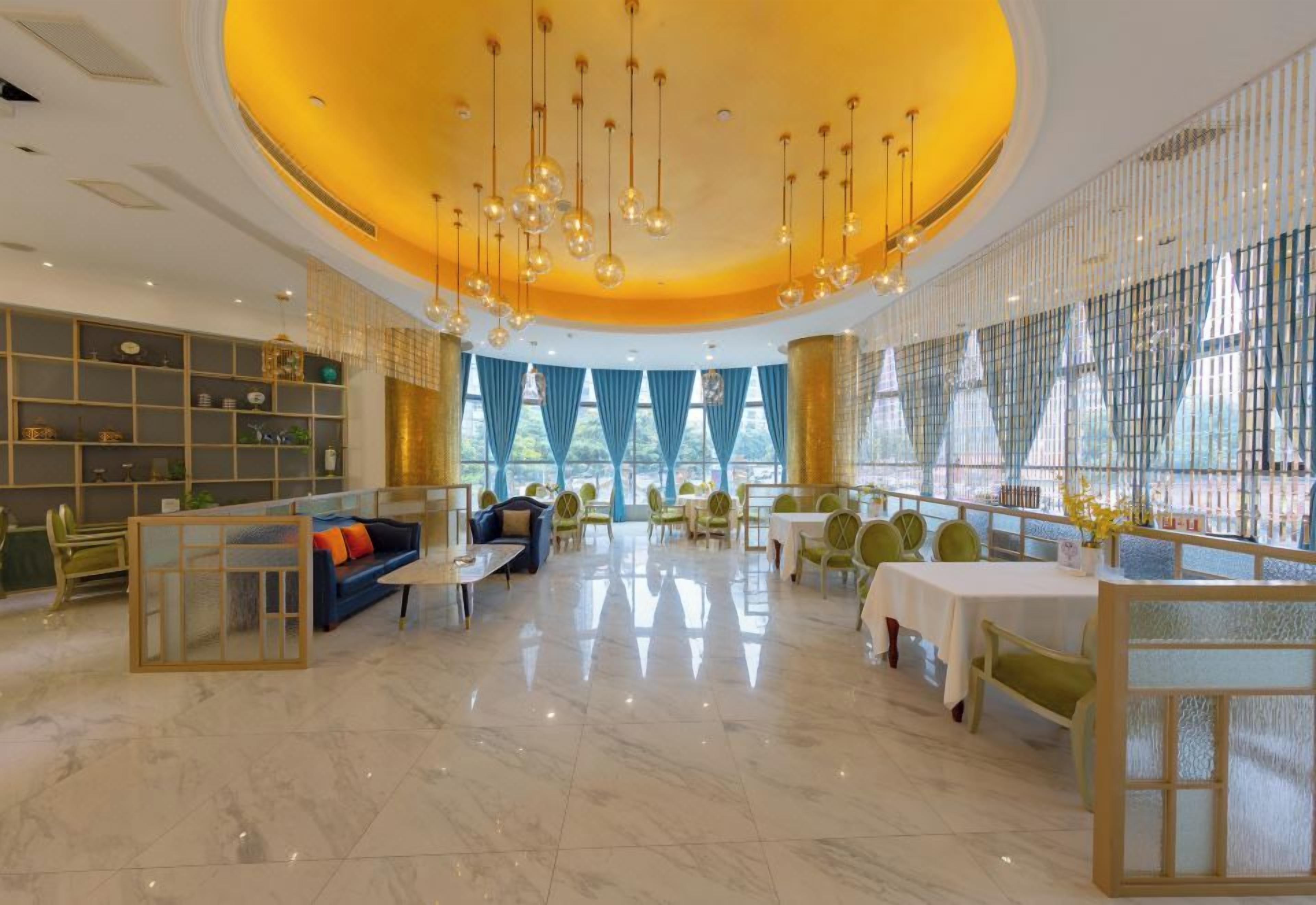 Eine geräumige Hotelhalle mit einer zentralen Sitzecke, einer Bar und einem Essbereich.