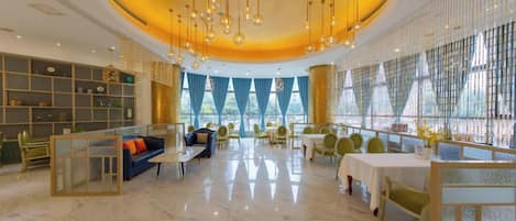Un amplio vestíbulo de hotel con una zona de estar central, un bar y una sección de comedor.