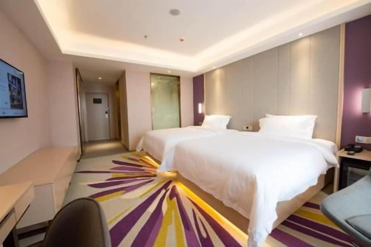 A hotel room with two beds, a desk, and a chair.