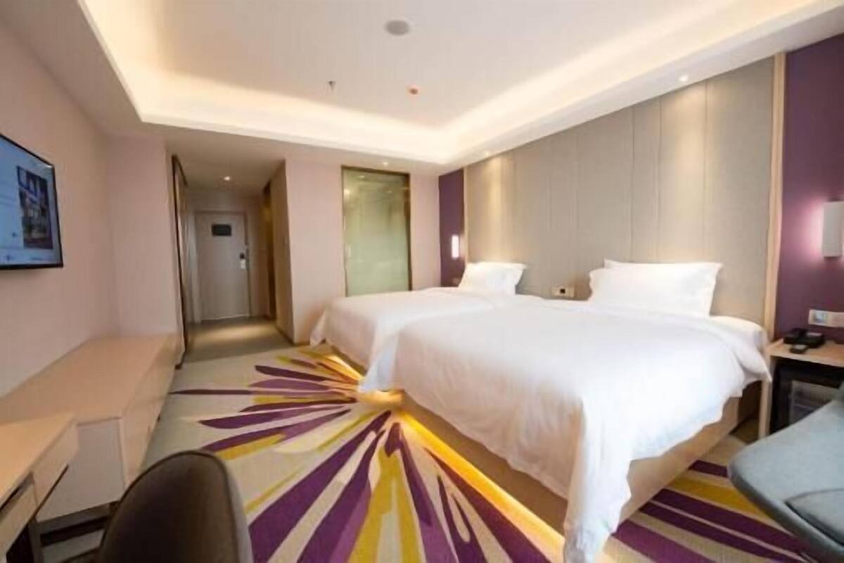 Quarto de hotel com duas camas, uma escrivaninha e uma cadeira.