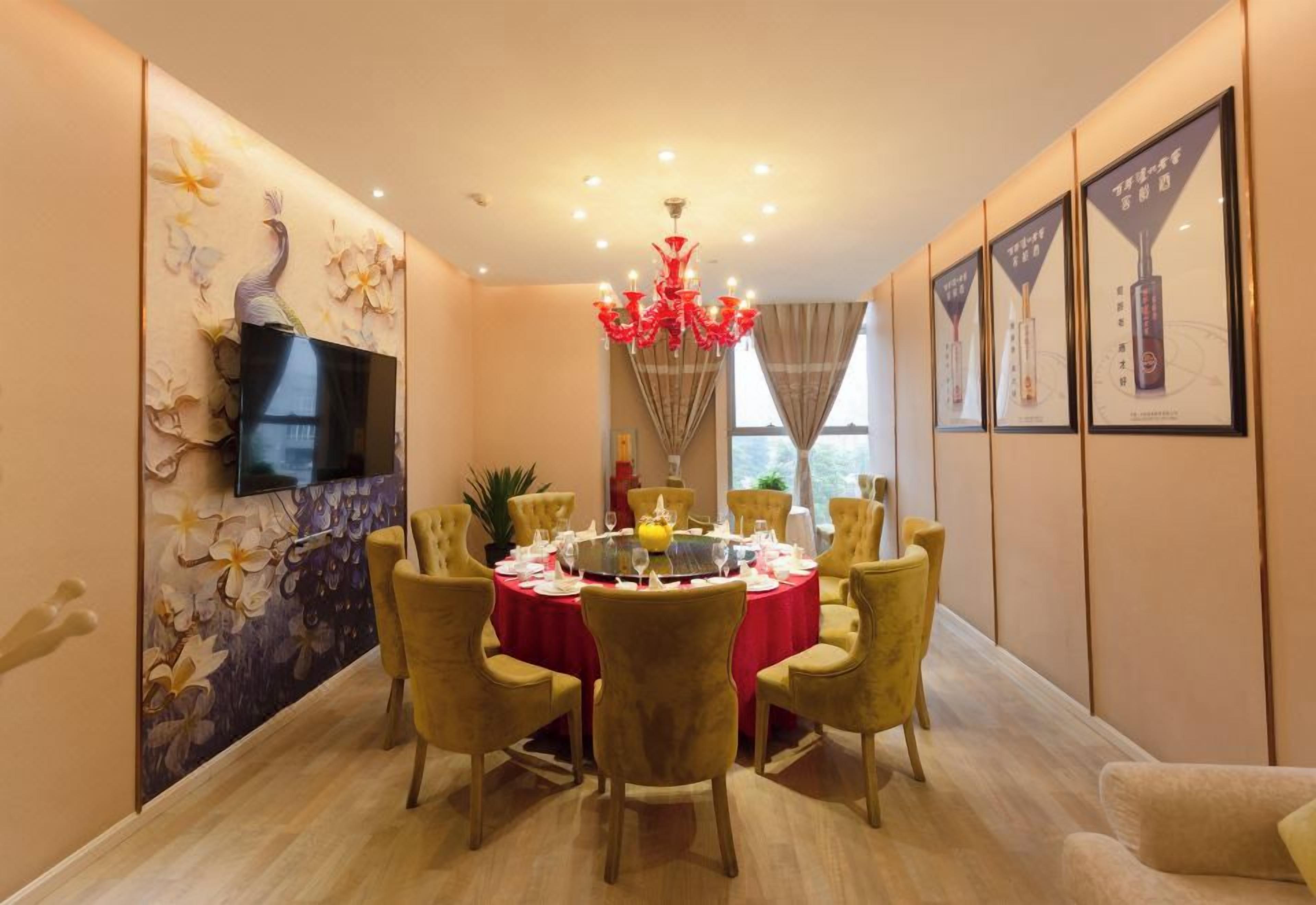 A dining area with a round table, chairs, a chandelier, and wall-mounted artwork.