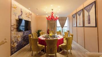 A dining area with a round table, chairs, a chandelier, and wall-mounted artwork.