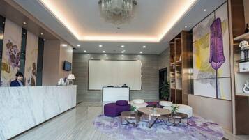 Un vestíbulo de hotel con una recepción, área de descanso y obras de arte en las paredes.