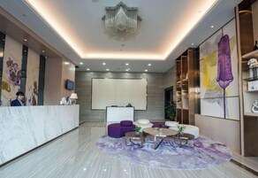 Un vestíbulo de hotel con una recepción, área de descanso y obras de arte en las paredes.