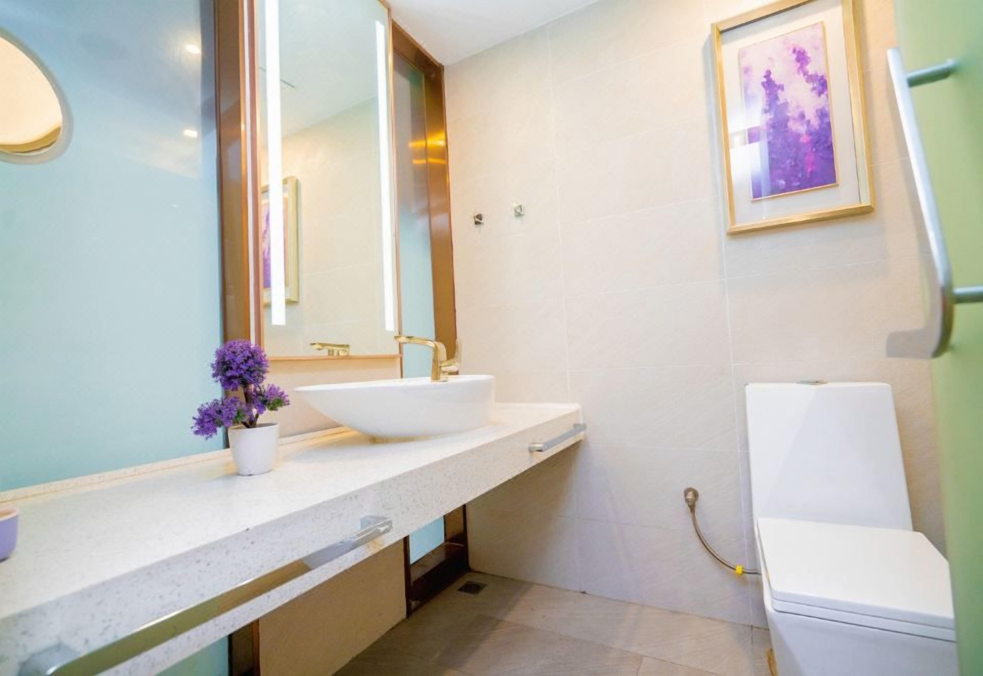 A modern bathroom with a white sink, a large mirror, and a toilet.
