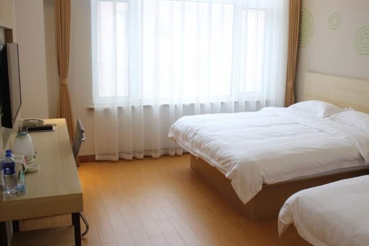 A hotel room with a bed, a desk, a chair, a TV, and a window with curtains.