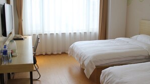 A hotel room with a bed, a desk with a computer, and a window with curtains. - Greentree Inn Express (Dalian)