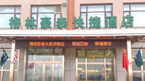 A hotel entrance with large glass doors, a red carpet, and flags. - Greentree Inn Express (Dalian)